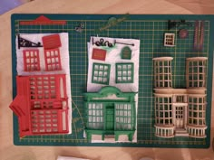 a green cutting board topped with cut out buildings