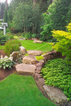 a garden with green grass, rocks and trees