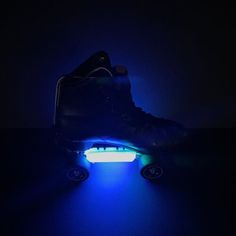 an illuminated skateboard in the dark with its wheels glowing blue and white on it