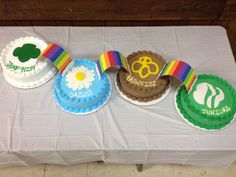 there are four cupcakes on the table with ribbons and rainbow ribbon around them