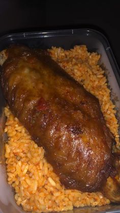 a plastic container filled with rice and meat covered in gravy on top of it