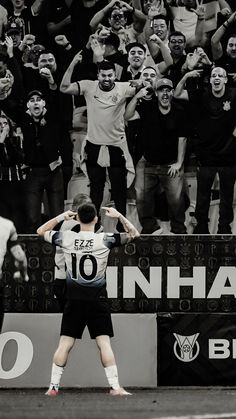 a man standing on top of a soccer field holding his hands up in the air