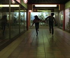 two people walking down a hallway with glass walls