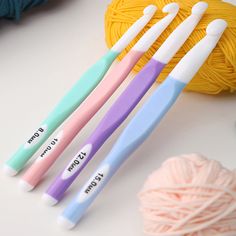 three toothbrushes sitting on top of a table next to yarn and balls of yarn