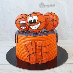 an orange cake with three basketballs on top and one is decorated like a face