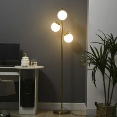 a living room with a computer desk, chair and lamp on top of the floor