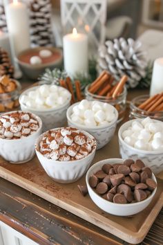 there are many desserts in bowls on the table with candles and pine cones behind them