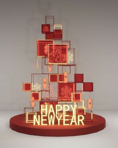 a happy new year display with red and gold squares on it's base, in the shape of a christmas tree