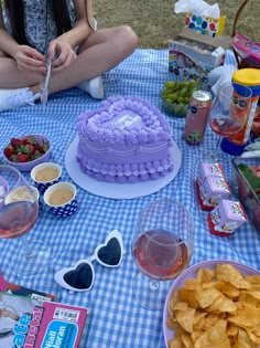 a woman sitting in front of a cake on top of a blue and white checkered table cloth