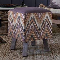 a foot stool sitting on top of a rug next to a wooden table and chair