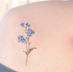 blue flowers on the back of a woman's lower back neck and upper arm