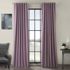 a living room with purple curtains and a gray chair in front of a large window