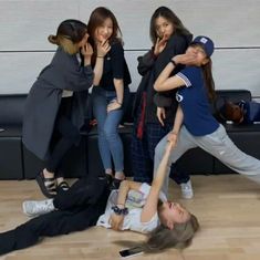 a group of people standing around each other on the floor in front of a couch