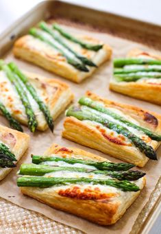 asparagus and cheese puff pastry on a baking sheet with some cut in half