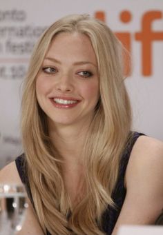 a beautiful blonde woman sitting at a table with a glass of water in front of her