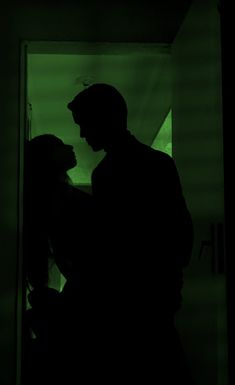 a man and woman standing next to each other in the dark