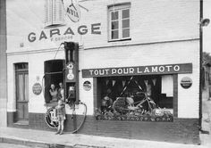 an old black and white photo of a gas pump in front of a storefront