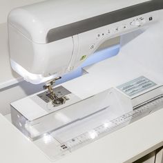 a white sewing machine sitting on top of a table next to a ruler and other items