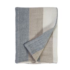 a blanket that is folded up on top of a white surface with blue and beige stripes