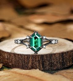 an emerald colored ring sitting on top of a tree stump