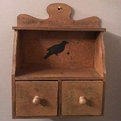 a wooden shelf with two drawers and a black bird painted on the bottom one drawer