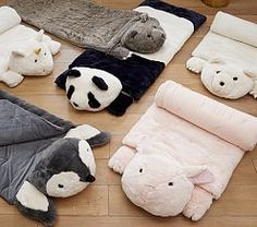 several stuffed animals are laid out on the floor next to blankets and pillows for sleeping