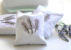 three embroidered pillows with lavender flowers on them