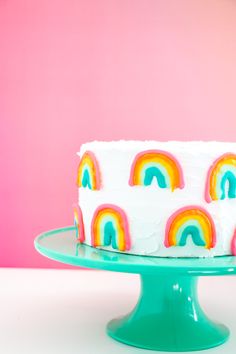 a cake with white frosting and rainbows on it sitting on a green plate