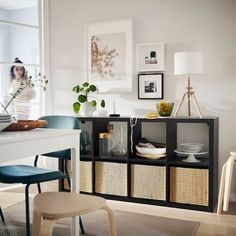 a dining room table and chairs with baskets on the shelves next to it, in front of a window