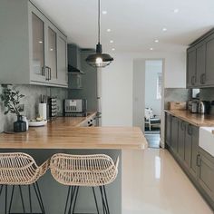 two wicker stools sit at the counter in this modern kitchen with gray cabinets and stainless steel appliances