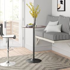 a small table with two stools next to it and a vase filled with flowers