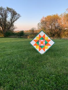 a patchwork quilt sitting on top of a lush green field