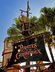 the pirates of the caribbean sign is next to a clock tower with palm trees around it