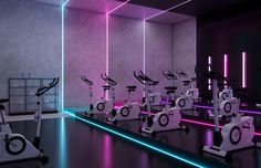 there are many exercise bikes in this room with neon lights on the walls and floor