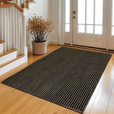 a black and white area rug on the floor in front of a door with stairs