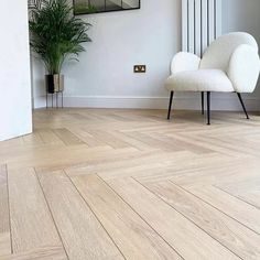 a white chair sitting on top of a hard wood floor next to a mirror and potted plant