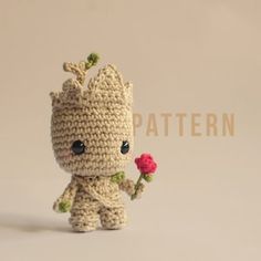 a small crocheted baby groote holding a flower in it's hand