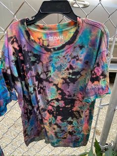 a tie dye shirt hanging on a chain link fence