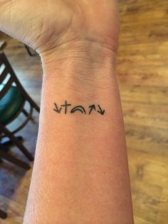 a woman's wrist tattoo with the word vat written in small black ink