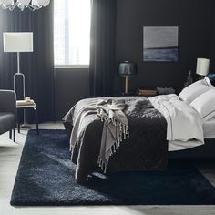 a black and white bedroom with a chandelier hanging from the ceiling, two chairs on either side