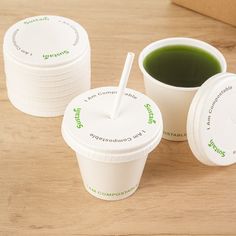 three cups of green tea sit on a table with their lids open and straws sticking out