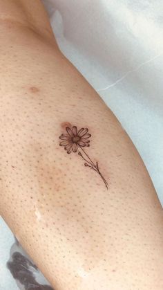 a small flower tattoo on the right arm and leg, with dots around it's edges