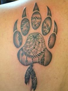 a tattoo on the back of a person's shoulder with a bear paw and dream catcher