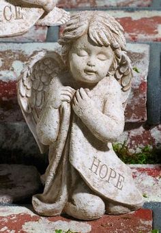 an angel statue sitting on top of brick steps with the word hope in two languages