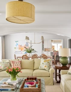 a living room filled with lots of furniture and flowers on top of a coffee table