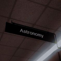 a black and white sign that says astronomy hanging from the ceiling in an office building