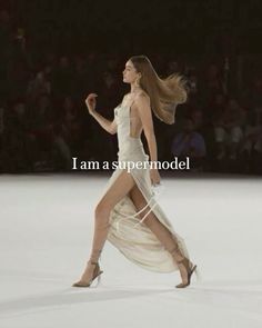 a woman walking down a runway in a white dress