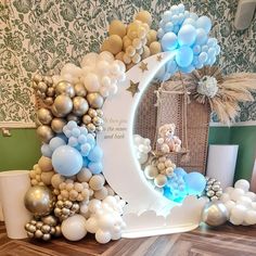 a balloon arch is decorated with balloons and a teddy bear sitting on the crescent moon