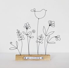 a wooden block with wire flowers on it and the words go outside written in black ink