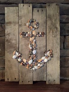 an anchor made out of rocks on top of a wooden pallet with shells in it